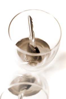 bourbon with keys inside glass on white background depicting drunk driving and addictions can kill in sepia