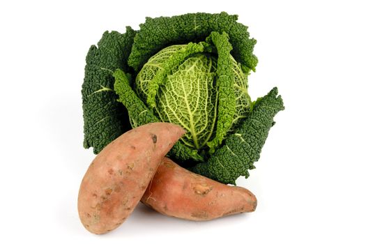 Single green cabbage with two pink sweet potatoes on a reflective white background