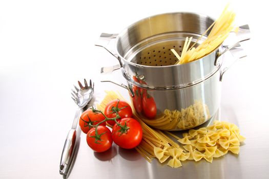 Stainless steel pot with uncooked pasta and tomatoes