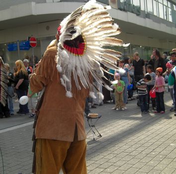 chieftain with traditional feather headdress in a pedestrianised area