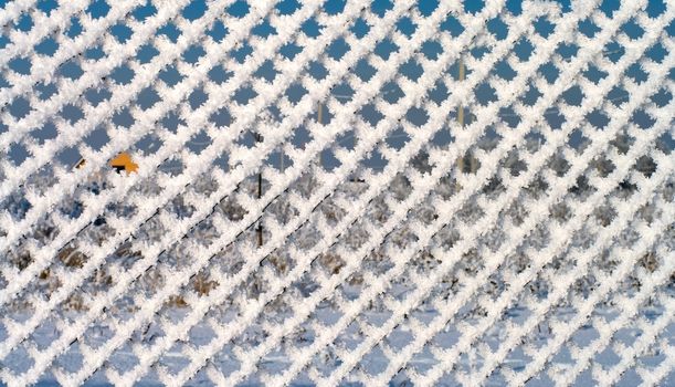 Background from a metal wire mesh fence covered with snow.