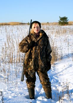 The female hunter on a winter field with a shot-gun.