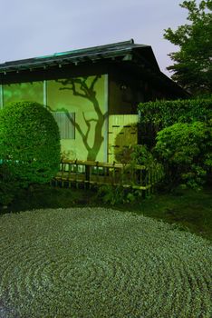 Japanese house wall with tree shadow and traditional circle pattern on the sand in zen garden by night time, Tokyo Japan