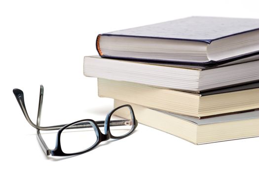 Books and reading glasses on white background