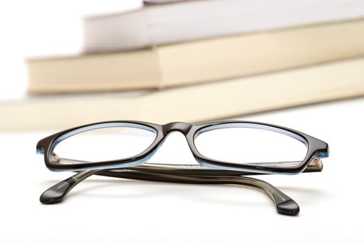 Books and reading glasses on white background