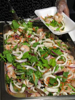 Caterer serves up seafood salad. Outside catering at Thai Culture Festival