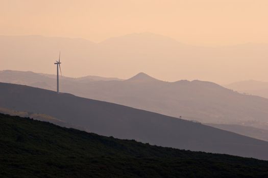 Wind turbine working on hill top at sunset