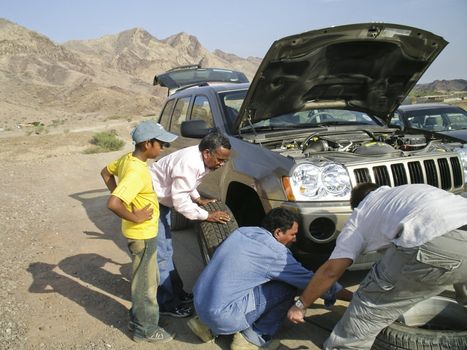 Team of men changing a wheel in the desert