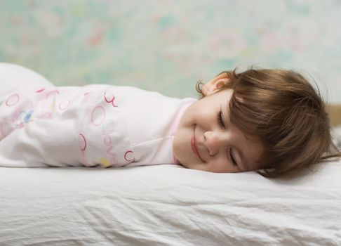 little girl with closed eyes, lying in bed and smile
