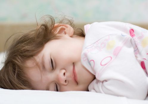 beautiful little girl with closed eyes lying in bed and smile