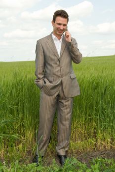 Agronomist. Businessman on a green field speaks by phone.