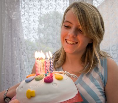 Pretty teenage girl blows out the candles on her birthday cake.