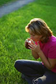 Woman with a cup of tea on a green grass