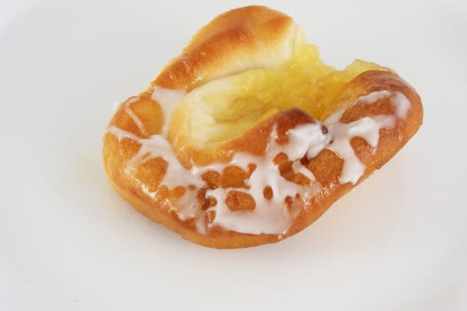 A pineapple danish roll with sugar icing.