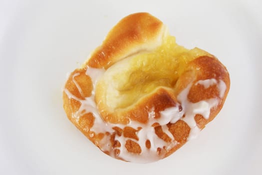 A pineapple danish roll with sugar icing.