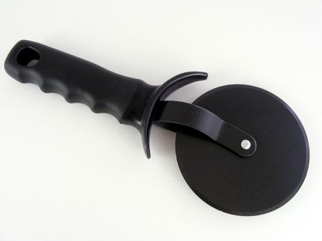 A black pizza cutter against an off-white background.