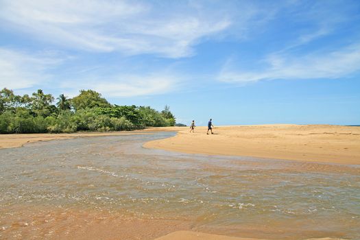 Couple walking across the sand of Machans Beach