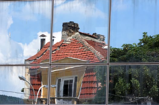 Old houses reflected in windows of  office building