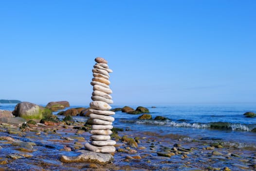 White pile of pebble among the boulders on the shore