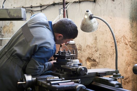 Worker and old gear in vintage workshop