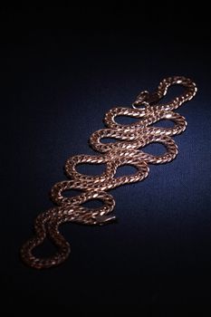 Nice gold chain lying on dark textiles background
