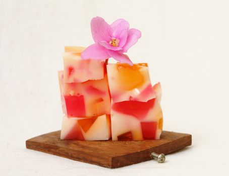             Pieces of jelly lying on a wooden desck, decorated with a violet                   