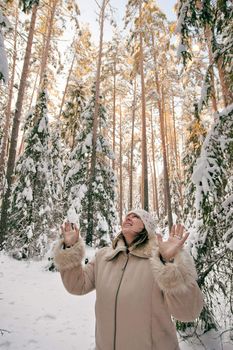 Happy middle-aged women having fun on winters day in forest.