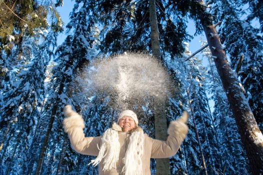 Happy middle-aged women having fun on winters day in forest.