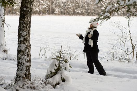 Happy middle-aged women having fun on winters day in forest.