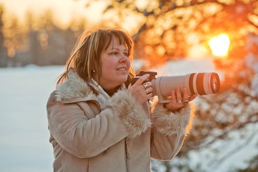 Happy middle-aged women photographer on winters sunset.