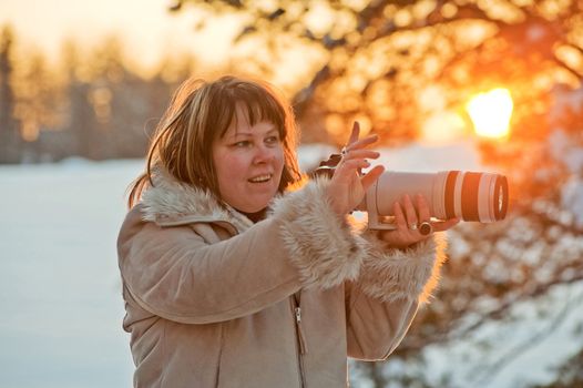 Happy middle-aged women photographer on winters sunset.