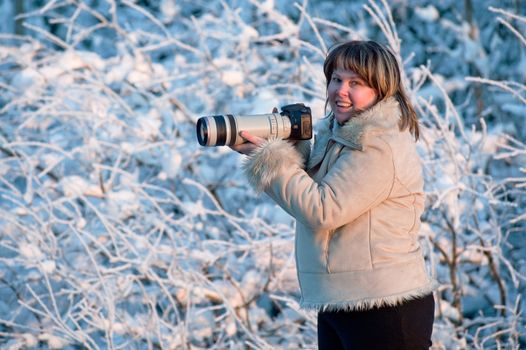 Happy middle-aged women photographer on winters day in forest.