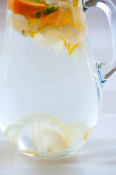 Jug of cold water with lemon and orange slices