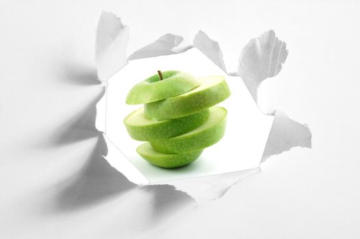 sliced apple fruit behind a hole in blank paper