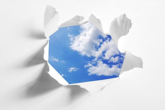 cloudy sky behind paper hole showing freedom