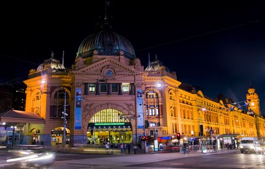 Flinders station at night in Melbourne, Australia. Cars, people and colorful combination of lights.