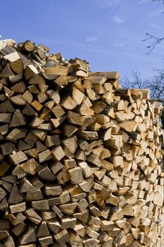 Cut, split and stacked firewood and blue sky. Lithuanian farm