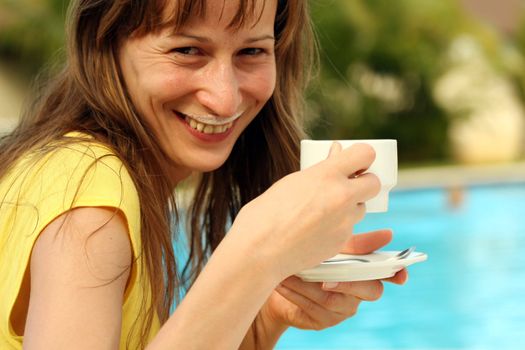 girl drinking a cup cappuchino by the pool