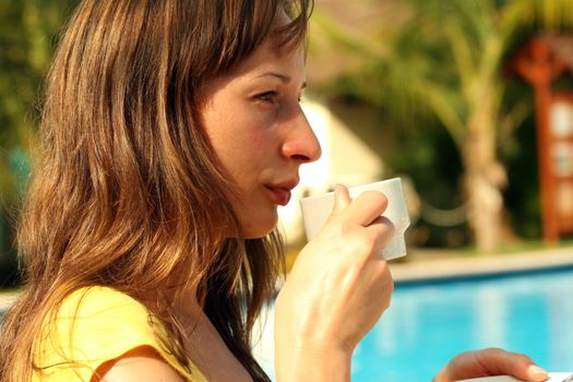 Woman by the pool with a cup coffee