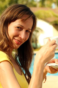 Girl with her coffee cup sitting by the pool