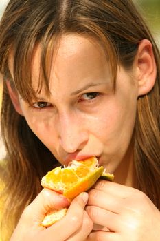 Pretty girl eating tasty and fresh orange