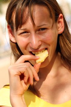 girl eating fresh and juicy ananas by the pool