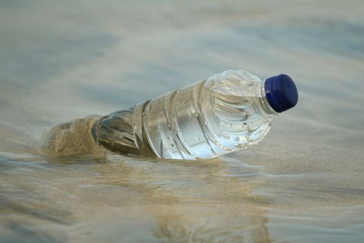 Plastic bottle in water on the sand beach 