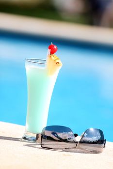 cocktail with sunglasses on the edge of the swimming pool