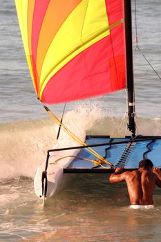 men pulling sailboat in the ocean