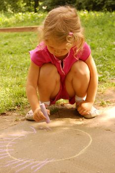 little girl drawing sun with chalk