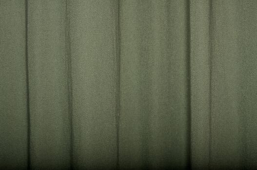 A green linen curtain, with light falloff towards bottom of frame to show texture