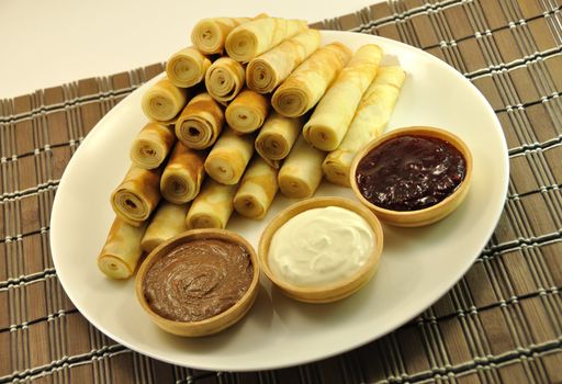 Rolled Pancakes with Cranberry Jam, Chocolate and Sour Cream on Bamboo Placemat