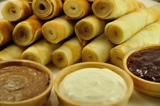 Rolled Pancakes with Cranberry Jam, Chocolate and Sour Cream, close-up