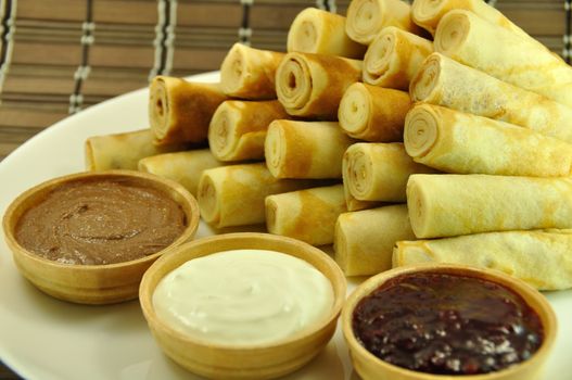 Rolled Pancakes with Cranberry Jam, Chocolate and Sour Cream on Bamboo Placemat